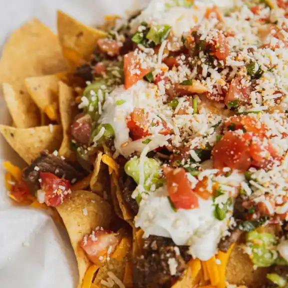 Loaded carne asada nachos topped with guacamole, sour cream, cheese, and pico de gallo