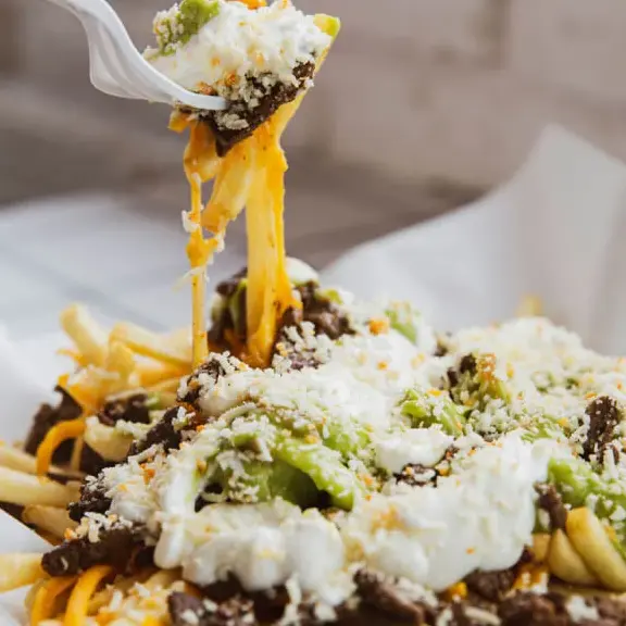 Carne asada fries with melted cheese, guacamole, and sour cream